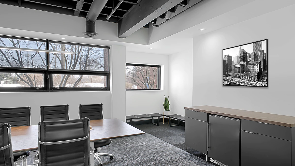 Office Interior Modern office conference room with wooden table, black chairs, large windows, a plant, and a framed cityscape photo.