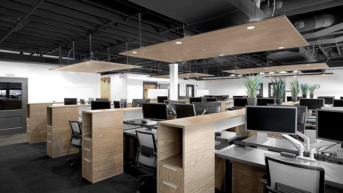 Office Interior Modern open-plan office with wooden cubicles, multiple computer stations, hanging ceiling panels, and potted plants.