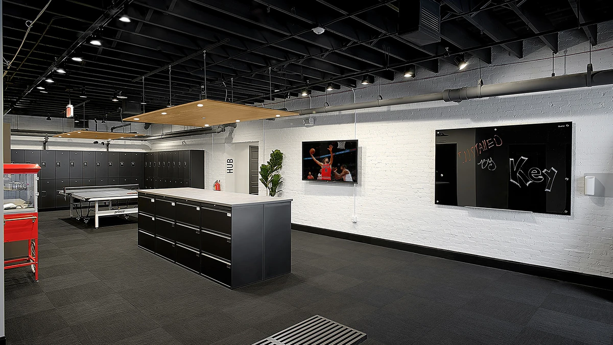 Office Interior Industrial-style workspace with black lockers, a central island cabinet, TV, chalkboard wall, and a potted plant.