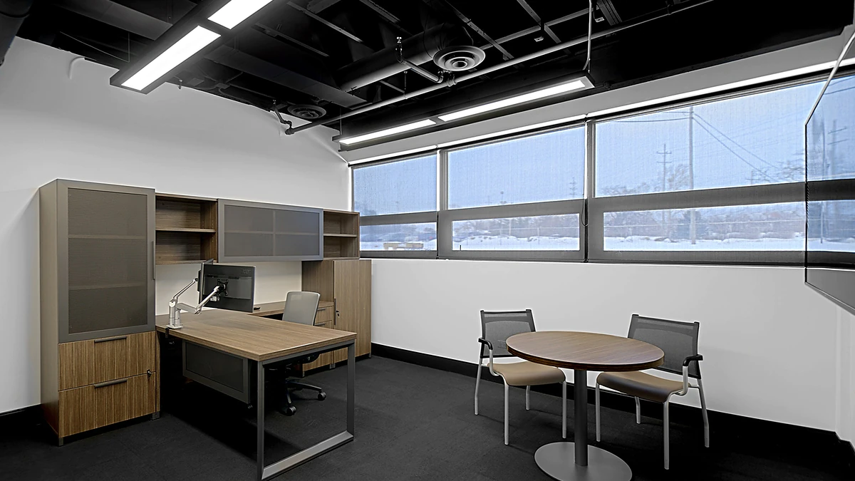 Office Interior Modern office interior with a wooden desk, computer, storage cabinets, and a round table with chairs near large windows.