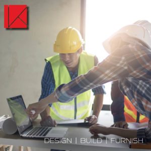 Three men discuss office construction with a laptop nearby