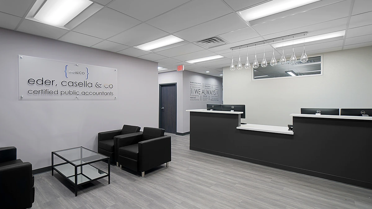 Office Interior Modern office lobby with a black reception desk, seating area, glass coffee table, and a wall sign for Eder Casella & Co CPAs