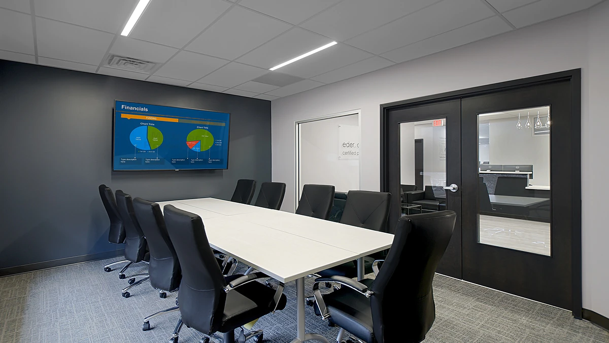 Office Interior Modern conference room with a long white table, black chairs, a wall-mounted screen showing charts, and glass doors.