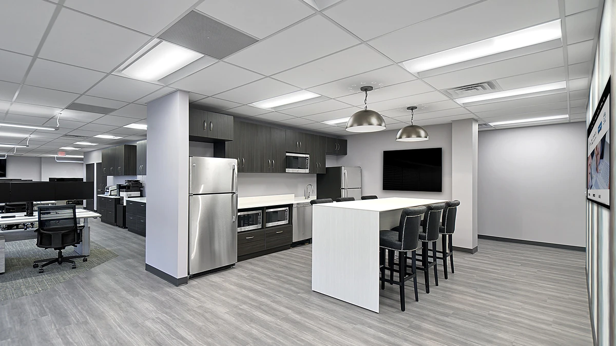 Office Interior Modern office break room with stainless steel fridge and appliances, a white island with bar stools, and a wall-mounted TV.