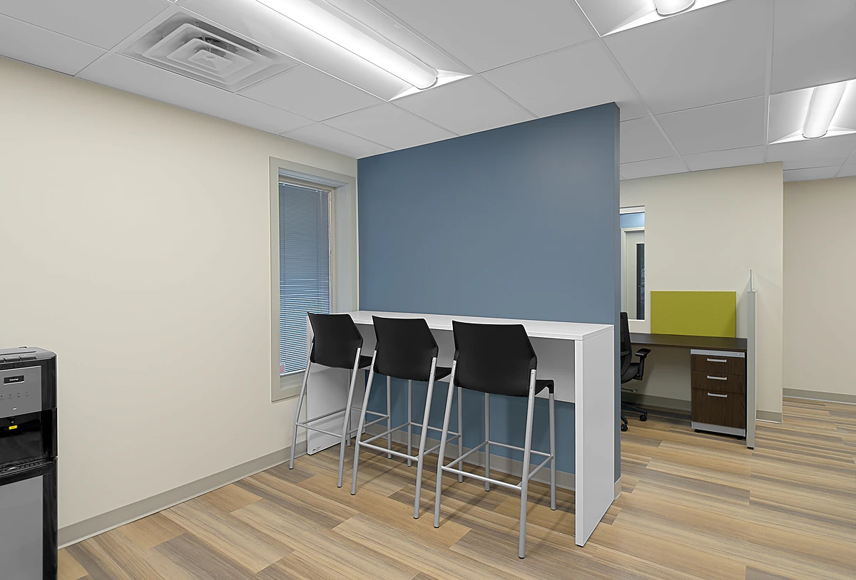 Office Interior Modern office break area with a blue partition, white counter, and four black stools, plus a window and desk.