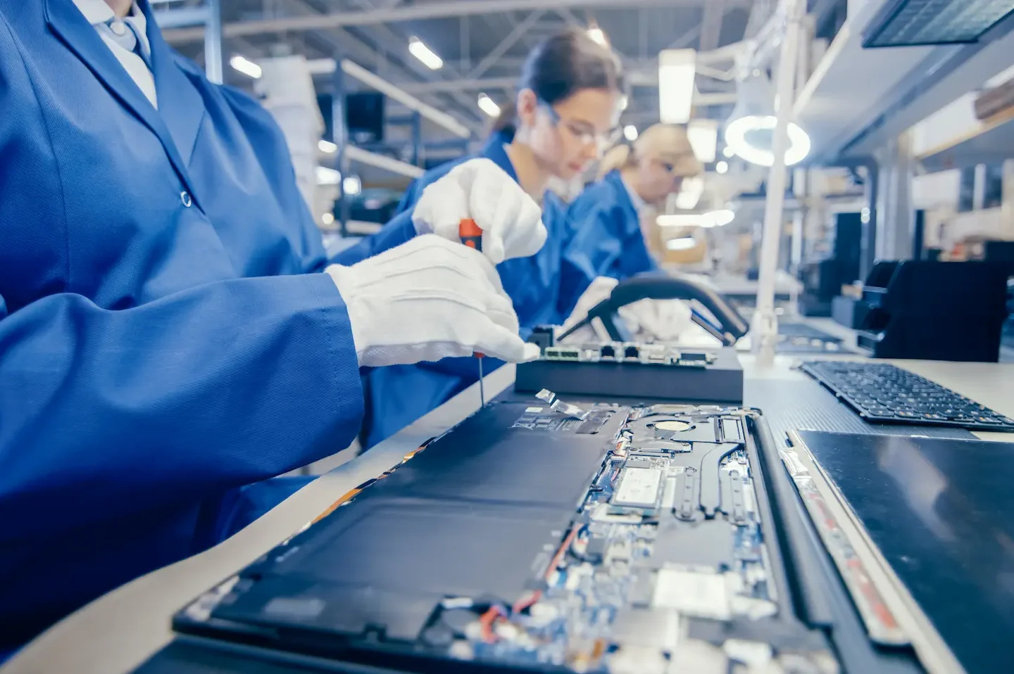 Technician testing grounding connections and ESD protection at an electronics manufacturing workstation.